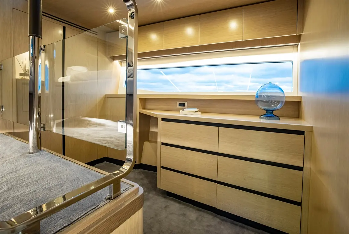 Modern yacht interior featuring polished wood furnishings, glass partitions, a decorative globe, and panoramic windows.